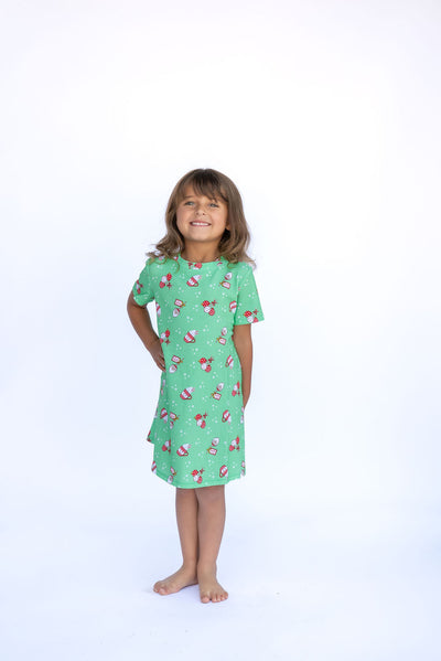 Young girl wearing a green nightgown with pink flamingo pattern on a white background