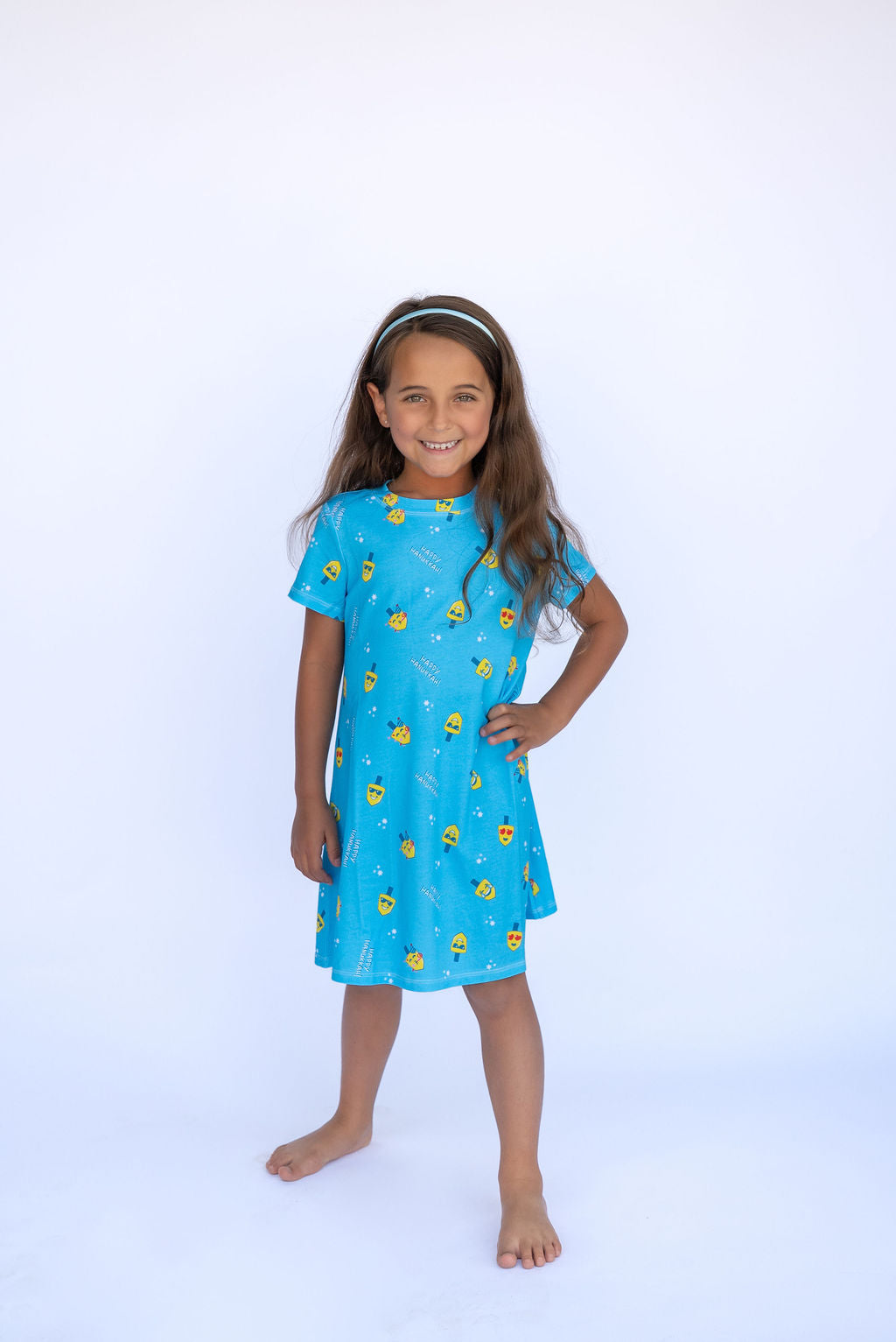 Young girl wearing a blue dress with yellow patterns on a white background
