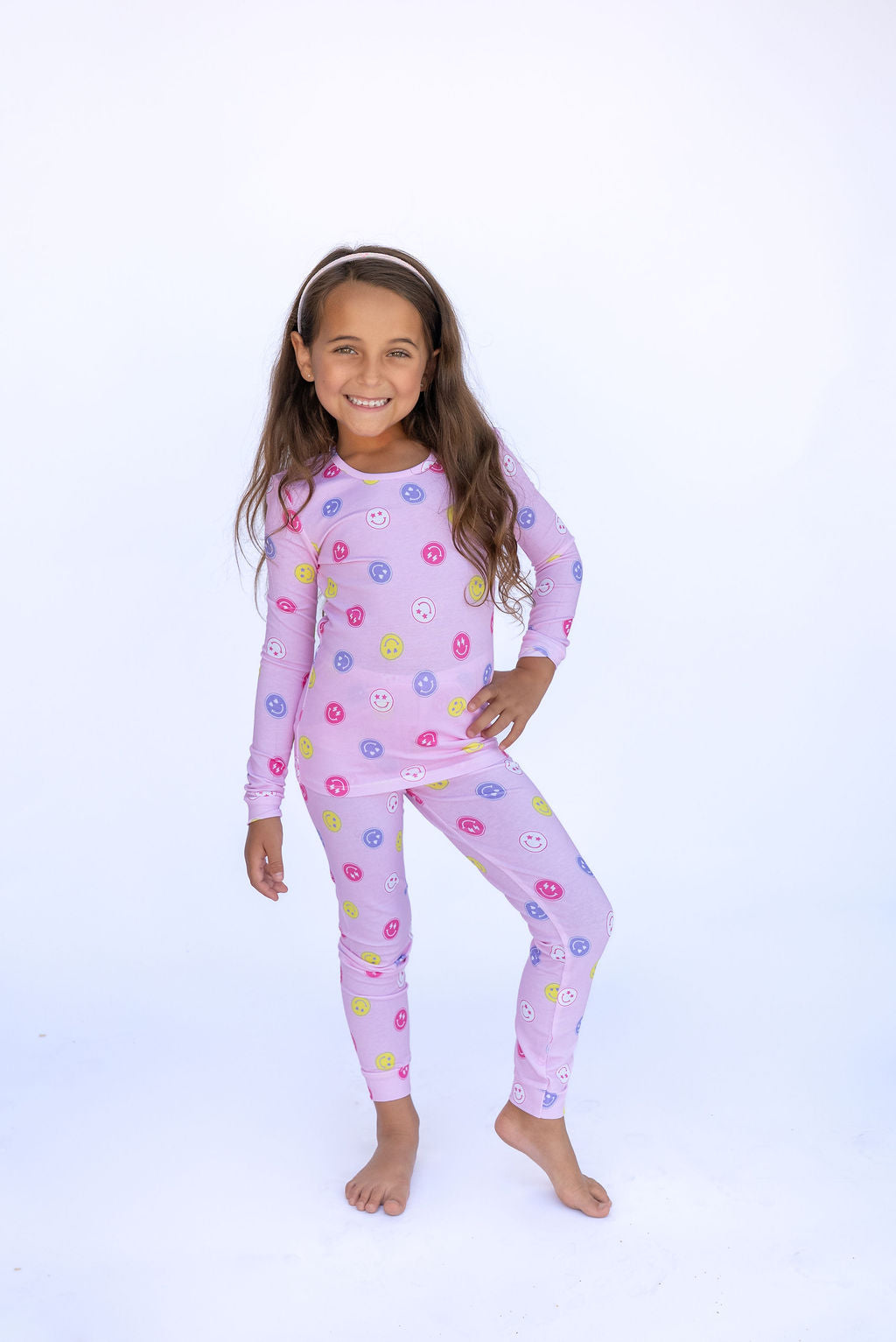 Girl wearing pink pajamas on a white background. 