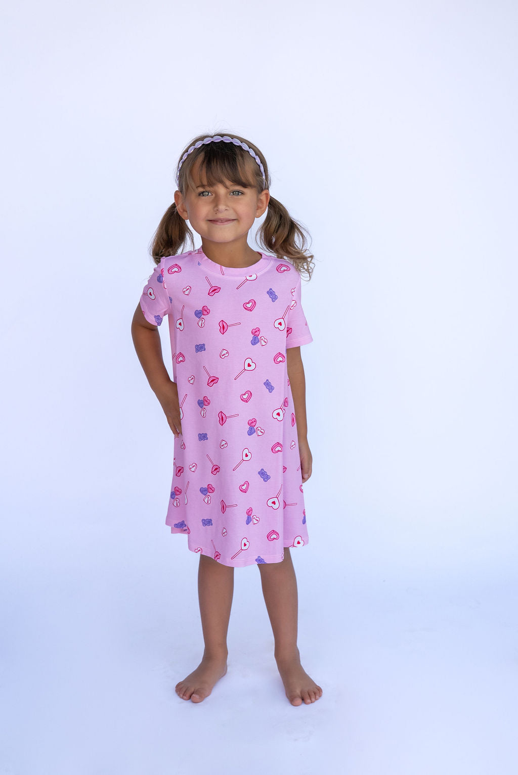 Young girl wearing a pink dress with a candy pattern on a white background
