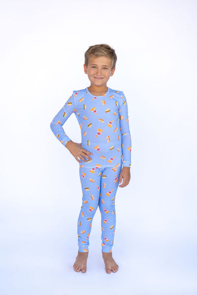 Child wearing a blue pajama set with pizza print on a white background
