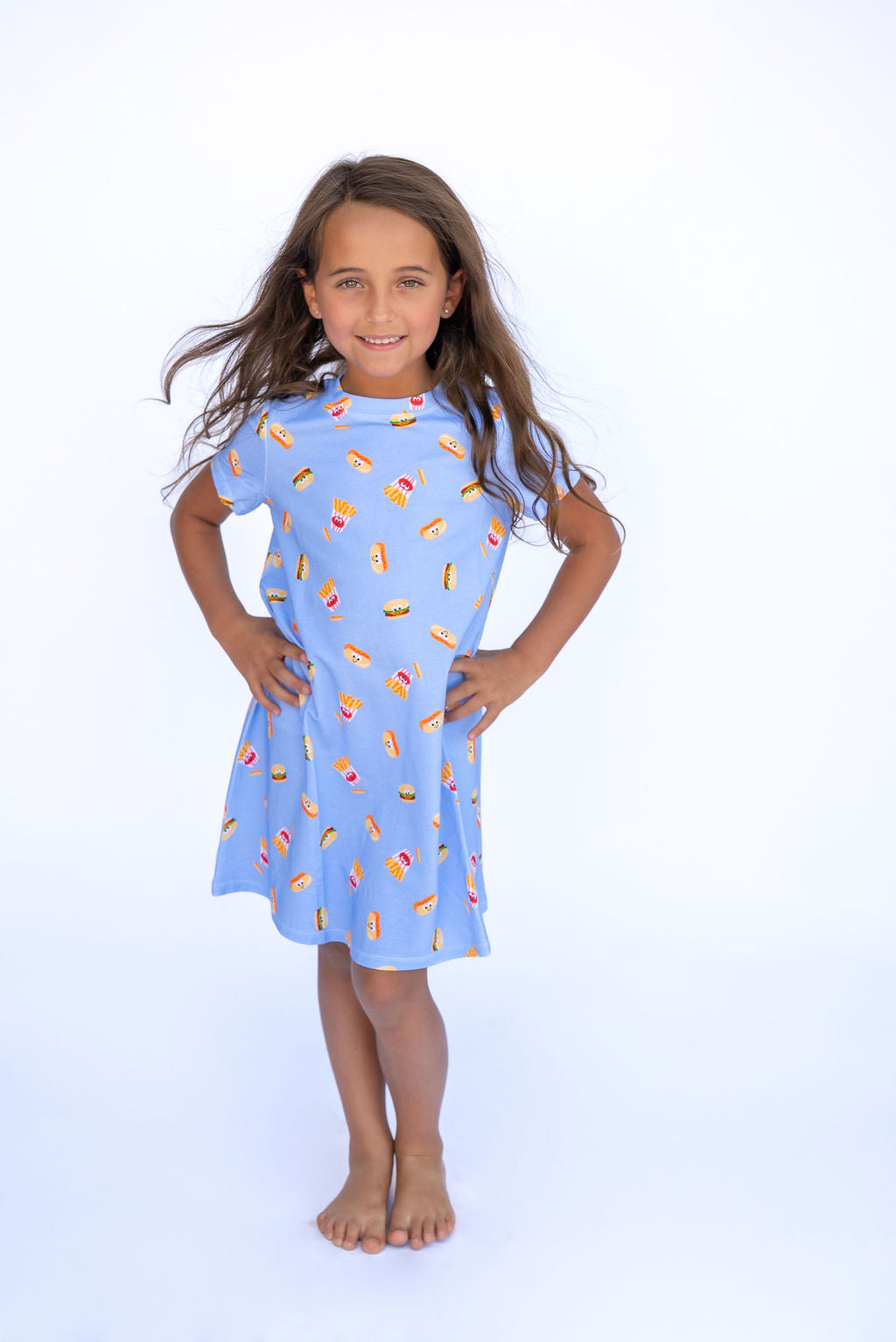 Young girl wearing a blue dress with food print on a white background
