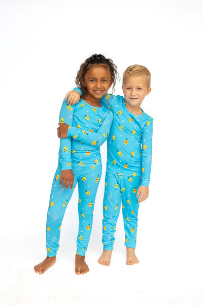 Two children wearing matching blue pajamas with yellow patterns on a white background