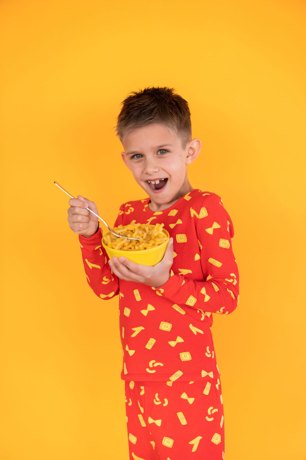 Boy in pasta PJs, eating pasta
